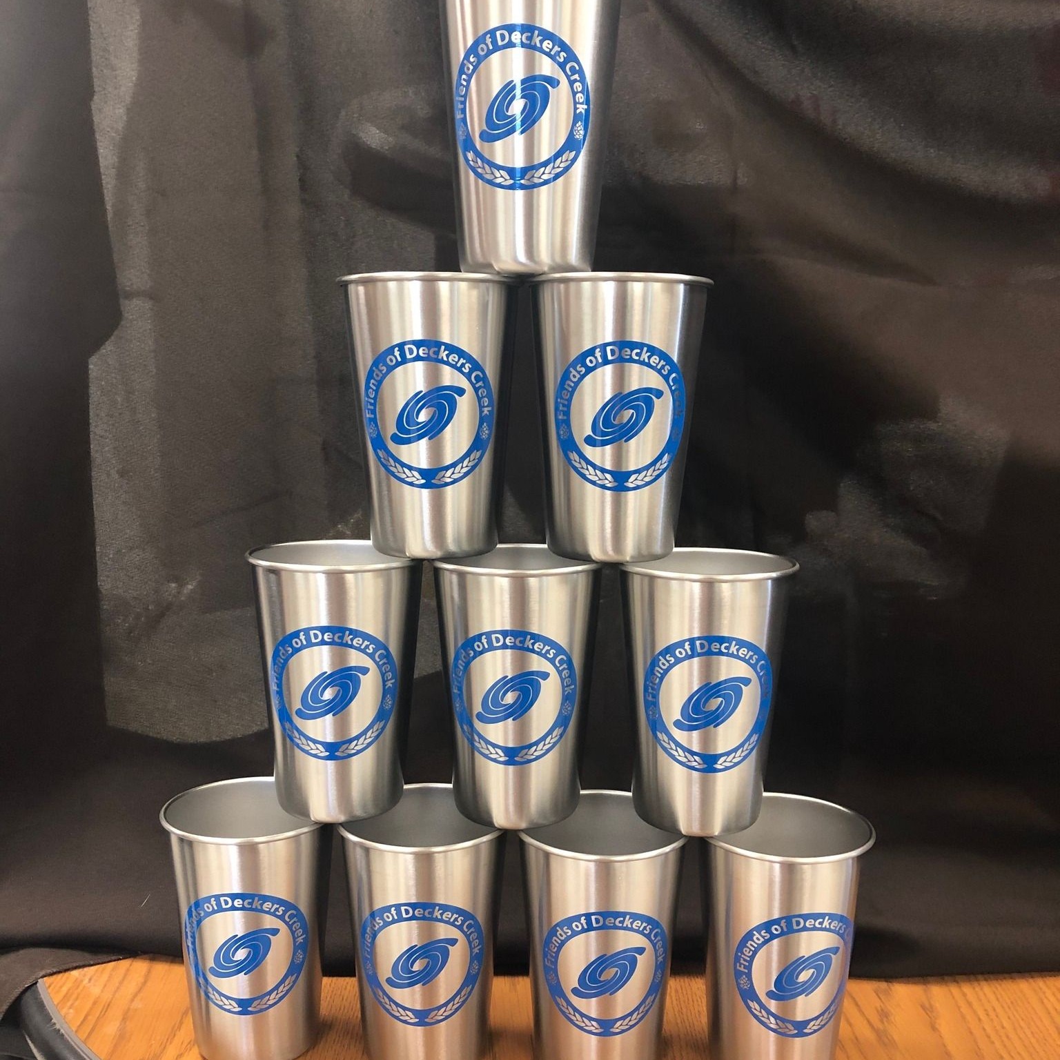 Reusable Metal FODC pint glasses stacked up on one another in a pyramid.